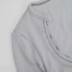 Close-up of the light gray ribbed knit texture and neckline of the long sleeve bodysuit