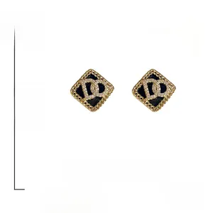 Détail macro de boucles d'oreilles logo CD avec bord doré et dimensions 1,7x1,3 cm