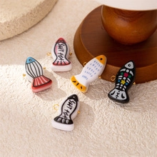 Macro shot of colorful small fish charms in red, blue, and black with golden hanging rings