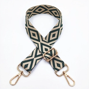 Detail of dark green and beige geometric diamond pattern woven bag strap with gold buckle