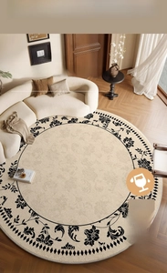 Detail of round cream carpet with black floral and diamond patterns on wood floor