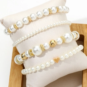 Elegant four-piece beaded bracelet set with white pearls, gold beads and a heart charm