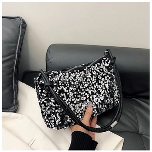 Close-up of shimmering silver sequins and black leather strap on a chic shoulder bag