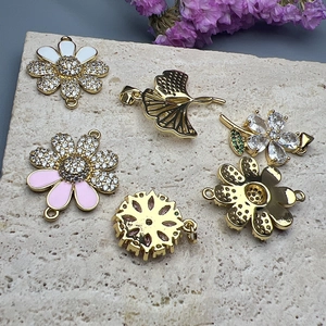 Golden daisy and maple leaf jewelry pendants with zircon and enamel on stone surface