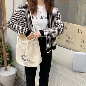 Détail de la texture velours côtelé et broderie œuf sur sac fourre-tout crème