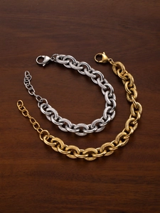 Detail of 18k gold and silver punk style chain bracelets with textured links on wood