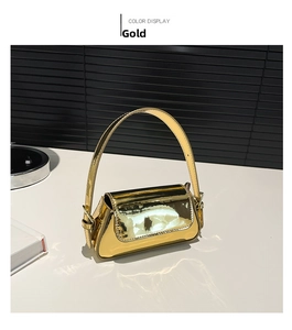 Detail of the high-gloss metallic gold finish and adjustable strap on the underarm bag