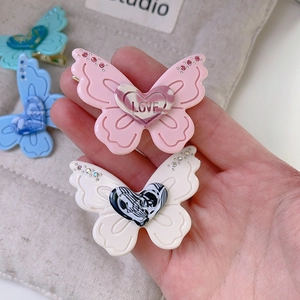 Detail of butterfly hair clip with rhinestones and marble heart LOVE inscription