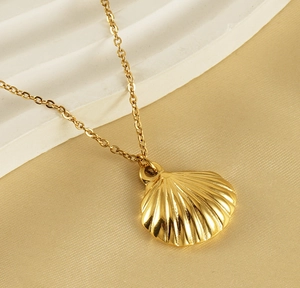 Close-up of golden fan-shaped necklace with shell texture on silky background