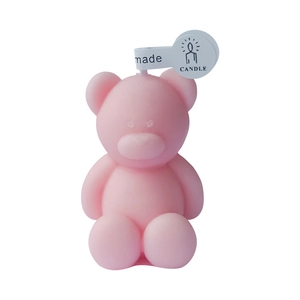 Pink bear shaped handmade scented candle with label on a clean white background