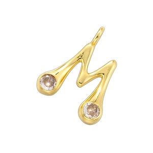 Macro shot of gold-plated bamboo-style letter M pendant with sparkling gemstones