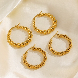 Boucles d'oreilles créoles dorées en acier inoxydable sur fond de soie beige élégant