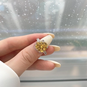 Close-up of a yellow round-cut diamond ring with side baguettes on a finger