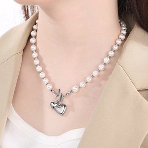 Close-up of pearl necklace with silver heart pendant and OT toggle clasp on model