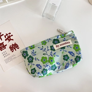 Close-up of floral embossed canvas pouch with silver zipper and By sozakka woven label