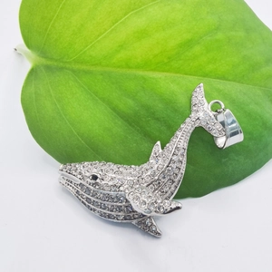 Hip hop gold plated whale pendant necklace with shimmering crystals on a green leaf