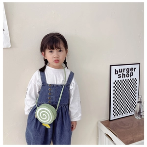 Close-up of a child wearing a green lollipop-shaped crossbody bag with spiral pattern