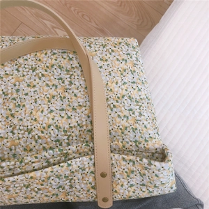 Detail of floral tote bag showing faux leather handle and antique bronze rivets