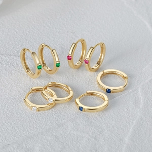 Macro detail of gold S925 silver hoop earrings with vibrant colorful gemstones