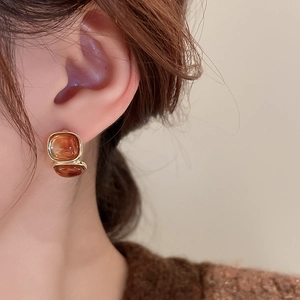 Macro detail of amber resin square earrings with gold plating and vintage geometric design