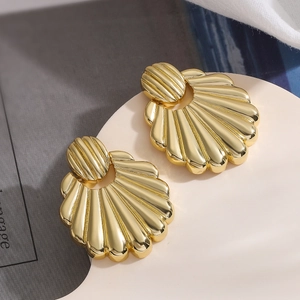 Detailed view of gold shell-shaped earrings on an artistic white pedestal setup