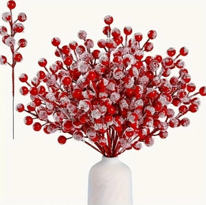 Detail of faux red berry branches with frosted snow effect in a minimalist white vase