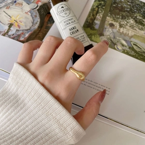 Détail d'une bague dorée irrégulière portée au doigt dans un cadre de vie élégant
