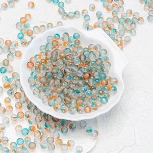 Macro shot of turquoise and amber frosted glass beads for jewelry making in a shell bowl