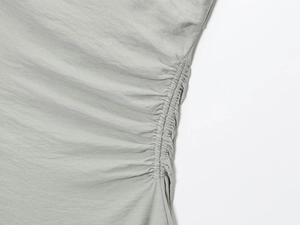 Gros plan détaillé sur les fronces latérales et les coutures d'une robe dos nu gris-vert