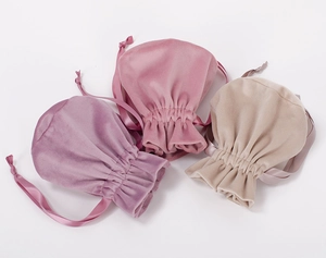 Flat lay of pink, purple, and beige velvet drawstring pouches with satin ribbon closure