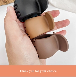 Three small plastic hair claw clips in black and brown colors held against a white background