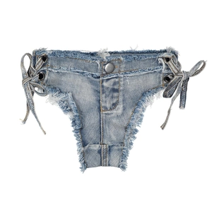 Dettaglio di pantaloncini di denim azzurro con frange e lacci sui lati del modello