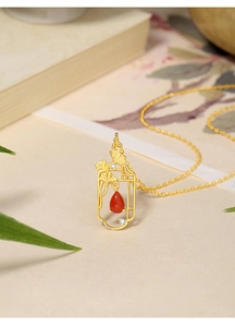 Detail of 925 silver necklace with ginkgo leaf, red teardrop agate, and gold finish