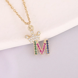 Detail of 18K gold crown and M letter pendant set with colorful zircon gemstones