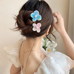 Detail view of pink and blue orchid hair clips with pearls worn on styled hair