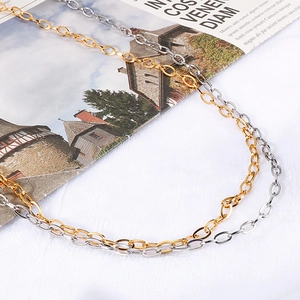 Colliers cœur en acier titane argenté et doré posés sur un magazine élégant