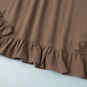 Détail de l'ourlet à volants marron sur la robe avec finition en tissu texturé vertical