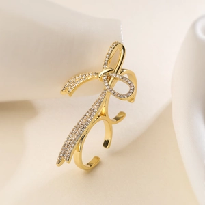 Irregular geometric 18K gold plated bow ring with pave crystals on silk background