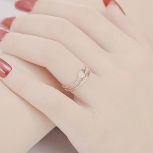 Close-up of heart-shaped and twisted rose gold titanium rings worn on a model's hand