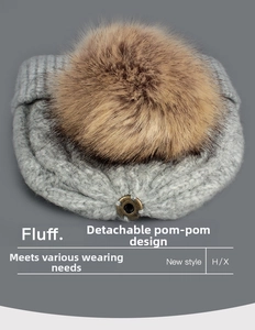 Close-up of light grey knit beanie featuring a detachable brown faux fur pompom detail