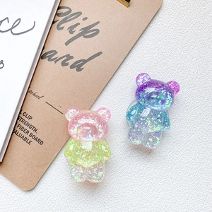 Détail des supports de téléphone en forme d'ours avec paillettes roses et bleues dégradées