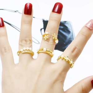 Set of four gold pearl rings with floral and wave designs for women on model hand
