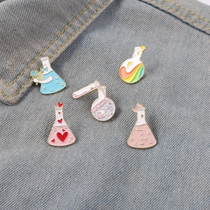 Set of 5 colorful cartoon enamel pins featuring laboratory test tubes and flasks on denim