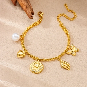Détail d'un bracelet à breloques en acier doré avec perles et cœurs sur un fond de sable doux