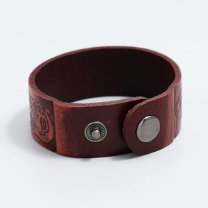 Detailed macro view of a brown vintage wide leather bracelet with embossed patterns