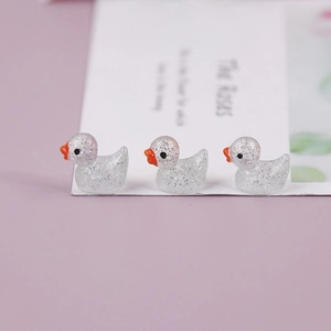 Three translucent white resin ducks with glitter finish on a soft purple background
