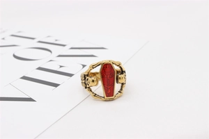 Detailed macro of a gothic gold ring featuring a red coffin center and skull accents