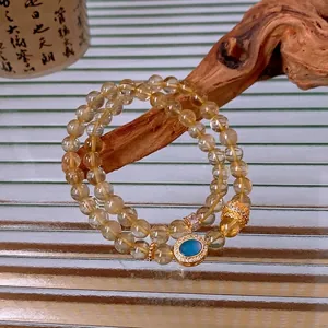 Double-layer rutilated quartz bead bracelet with an oval blue zircon pendant and gold accents