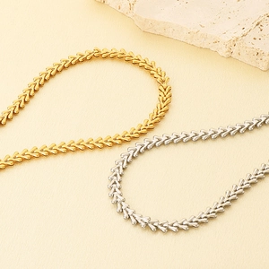 Detail of V-shaped wheat chain necklaces in gold and silver plating on stone display