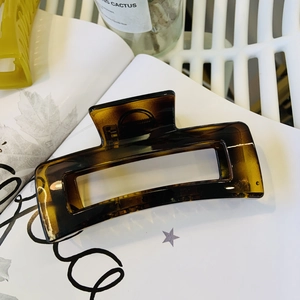 Close-up of a large amber tortoiseshell hair claw clip on a white vintage book